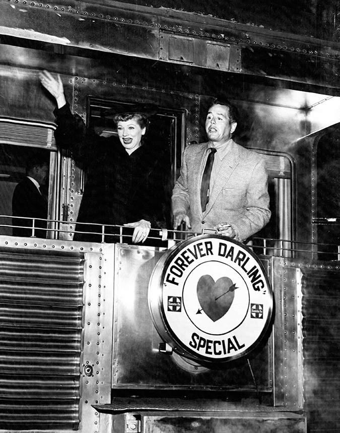 Actress and comedian Lucille Ball and her husband actor and musician Desi Arnaz stand on the rear platform of a Santa Fe Railway passenger car in 1956.