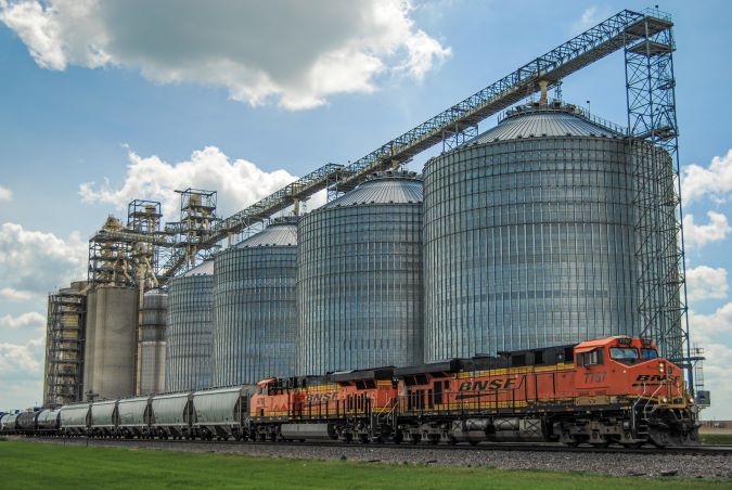 A BNSF grain train passes a grain facility 